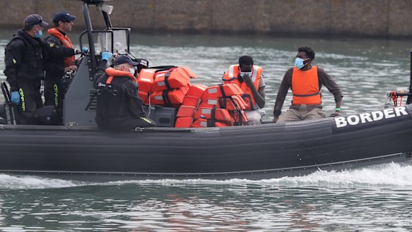 A Border Force vessel brings a group of migrants into the port city of Dover, England.