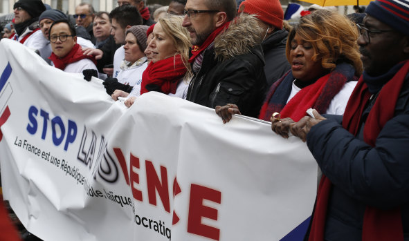 Protesters carry an anti-violence banner through the streets of Paris on Sunday.