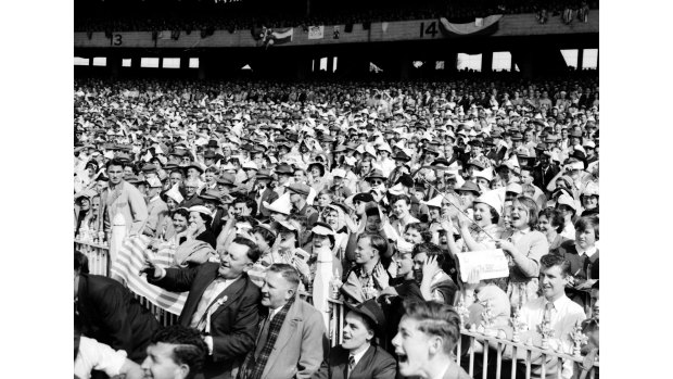 A sea of hats, suits and ties and best frocks. An immaculately dressed crowd watches the game.