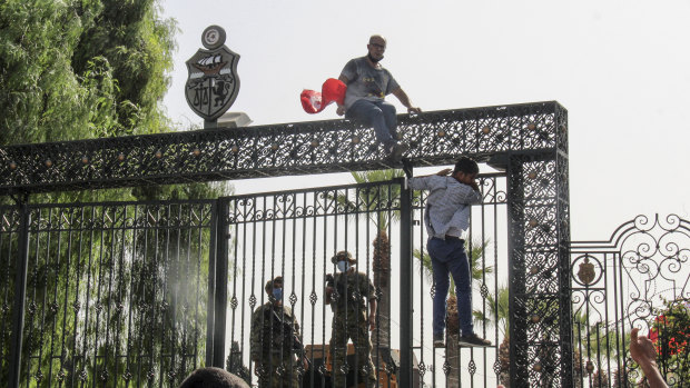 Tunisian soldiers guard the main entrance of the parliament as demonstrators gather outside the the gate in Tunis.