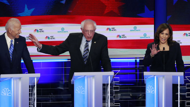 Democratic presidential candidate Senator Bernie Sanders, centre, gestures towards former vice-president Joe Biden as Kamala Harris talks.