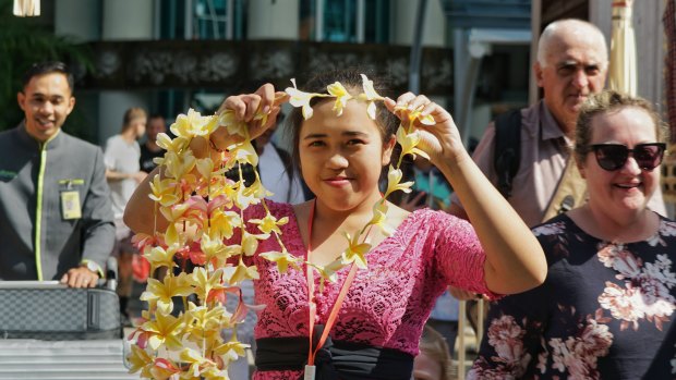 Wayan Ani passes out frangipani necklaces to visitors arriving at Bali Ngurah International Airport.
