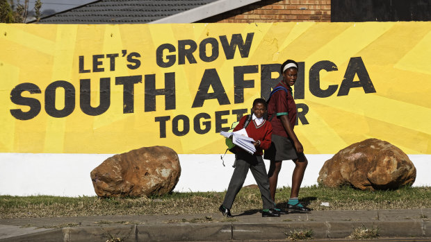 Schoolchildren walk home past an election mural for the ruling African National Congress (ANC) party in Johannesburg, South Africa.