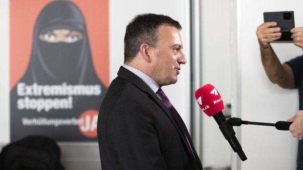 Walter Wobmann, National Councillor SVP, a supporter of the proposal to ban face coverings in front of a poster promoting the ban as a way to stop extremism.