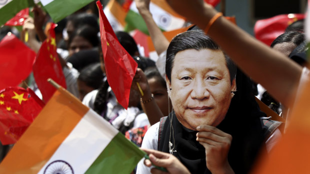 An Indian schoolgirl wears a mask of Chinese President Xi Jinping to welcome him last year. 