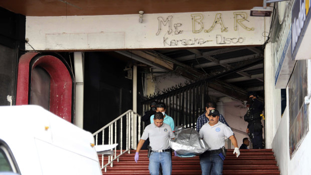 Workers from a forensic service carry the body of a man who was killed by gunmen inside a bar in Acapulco, Mexico. 