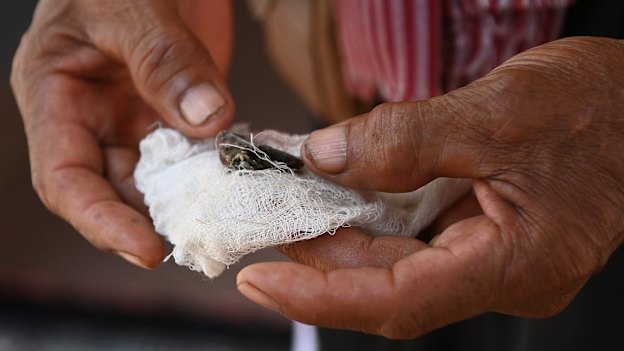 Khek Vin holds a piece of shrapnel removed from his body after his house was hit by artillery.