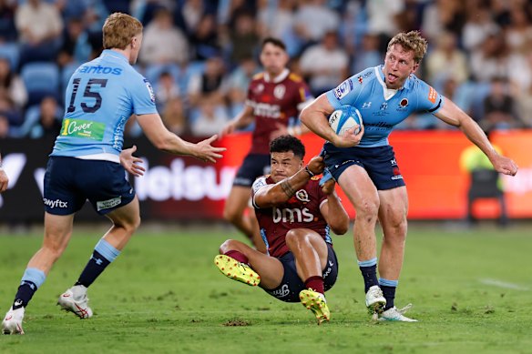 The Waratah’s Harry Potter is tackled by Hunter Paisami of the Reds, during their round one Super Rugby match.