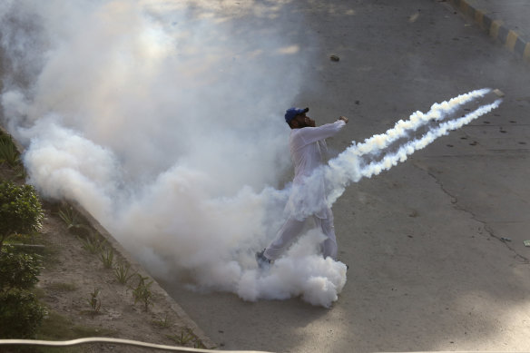 A supporter of Pakistan’s former prime minister Imran Khan hurls a tear gas shell back towards police in Peshawar.