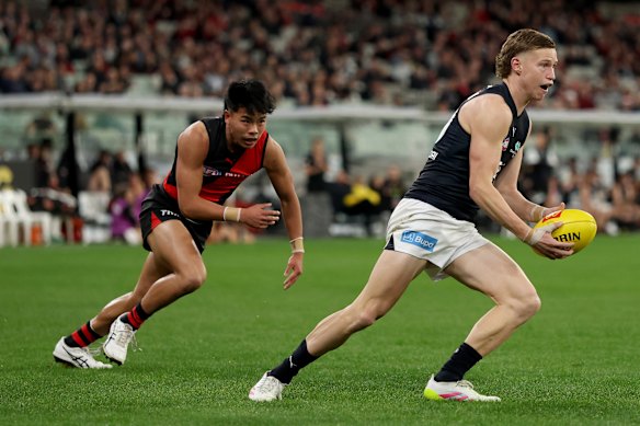 Flynn Young of the Blues runs with the ball under pressure from Bomber Jayden Nguyen.