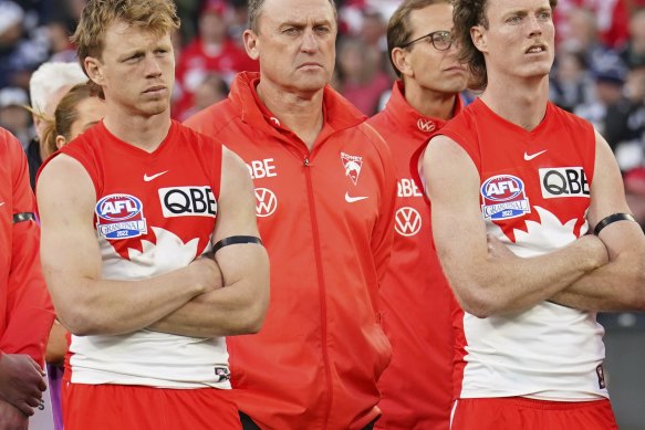 Callum Mills, John Longmire and Nick Blakey look on as Geelong players collect their premiership medals.