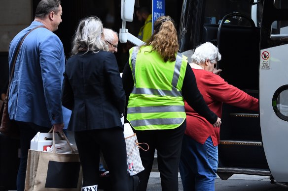 People board buses that are waiting to transport those leaving quarantine at the Swissotel.