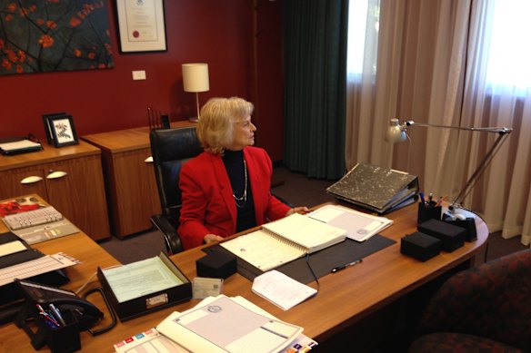 Patsy King, num momento de reflexão silenciosa, senta-se à mesa de seu sucessor no reboot da série de televisão Wentworth, durante uma visita ao set em 2013.