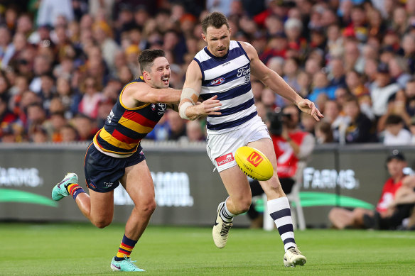 Patrick Dangerfield of the Cats and Chayce Jones of the Crows chase the footy.