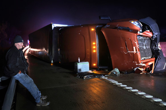 Mark Nelson waits with his tractor-trailer after it overturned during high winds and a possible tornado in Missouri.