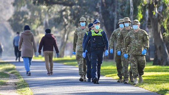 Police and ADF members patrol in Princess Park, Carlton on Friday.