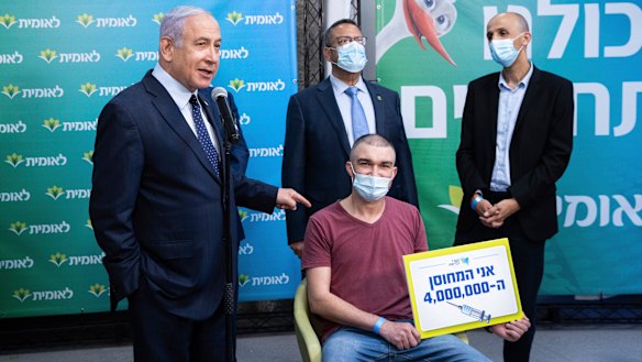 Prime Minister Benjamin Netanyahu, left, meets Theodor Salzen, seated, the 4 millionth person  to be vaccinated for the coronavirus in Israel.