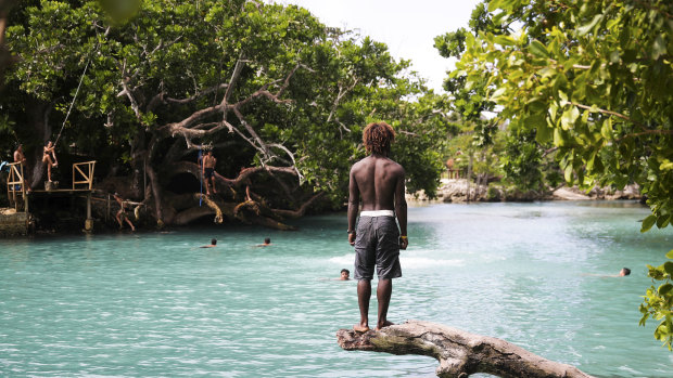 People swimming at the Blue Lagoon on Efate Island in Vanuatu with the rope swing visible on the left side.