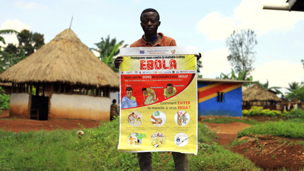 A man displays an Ebola information leaflet for residents in Mangina, Democratic Republic of Congo.