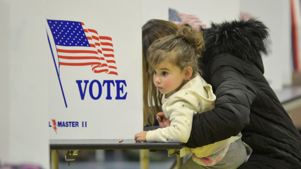 2 yaşındaki Emma Kent, annesi Melinda, Chesterfield, New Hampshire'daki bir sandıkta oy pusulasını doldururken etrafına bakınıyor.
