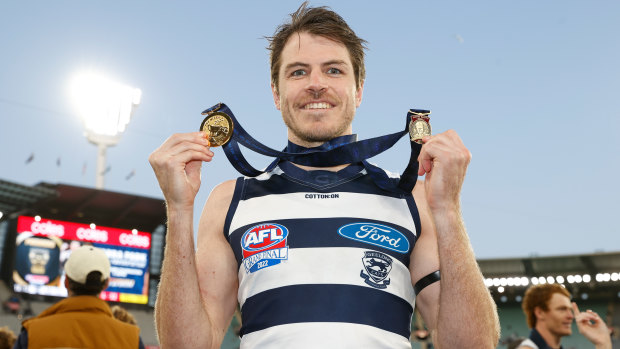 Isaac Smith poses with his 2022 Norm Smith and AFL premiership medals.