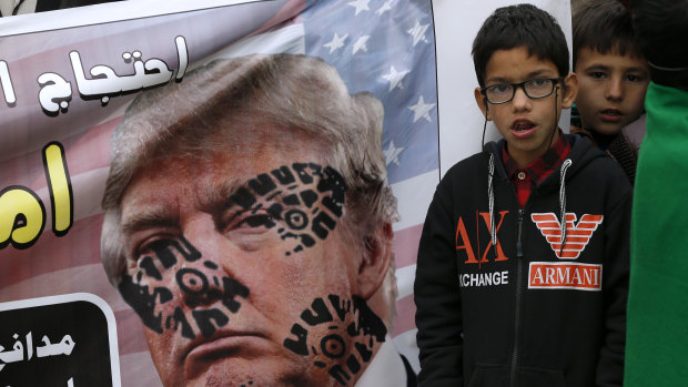 A boy next to a desecrated poster of US President Donald Trump during a rally  to condemn the killing of Iranian Revolutionary Guard General Qassem Soleimani.