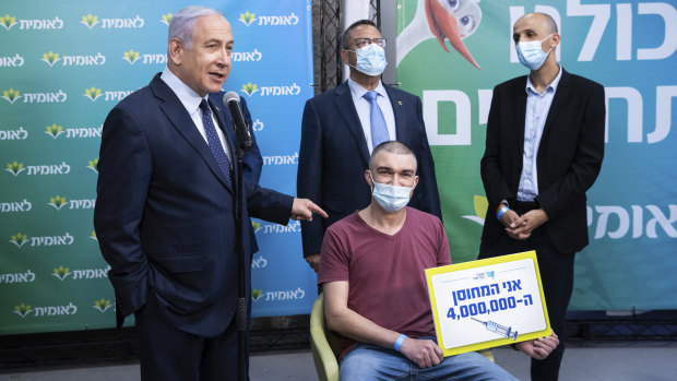 Prime Minister Benjamin Netanyahu, left, meets Theodor Salzen, seated, the 4 millionth person  to be vaccinated for the coronavirus in Israel.