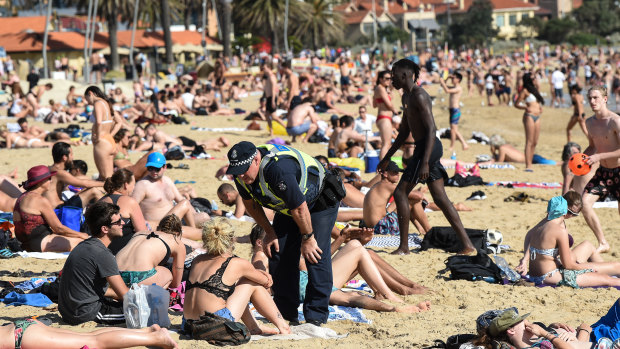 Police speak to beachgoers at St Kilda on Thursday. 