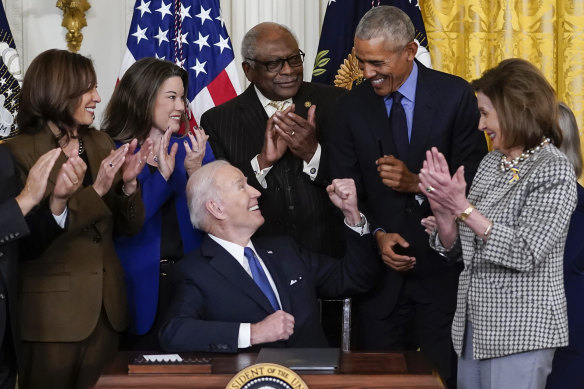 US President Joe Biden looks to his predecessor Barack Obama after signing an executive order in the White House in Washington, with James Clyburn and Nancy Pelosi behind him.