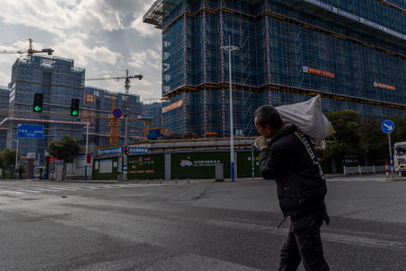 A migrant worker walks past an unfinished building in Wenzhou.