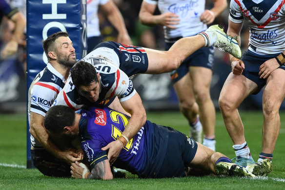 Kenny Bromwich of the Storm is held up over the try line by James Tedesco and Nat Butcher of the Roosters.