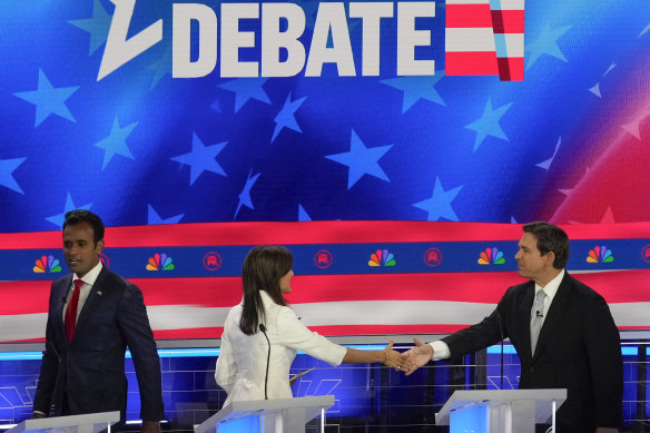 Former US ambassador to the UN Nikki Haley shakes hands with Florida Governor Ron DeSantis as businessman Vivek Ramaswamy walks past.