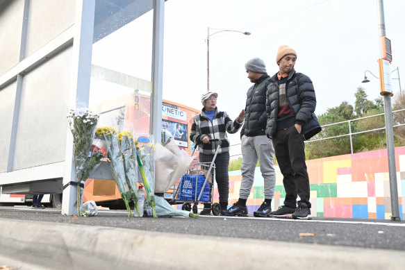Mourners, including Mawn Lyhym, leave flowers at the bus stop where Pasawm was killed on Thursday evening.