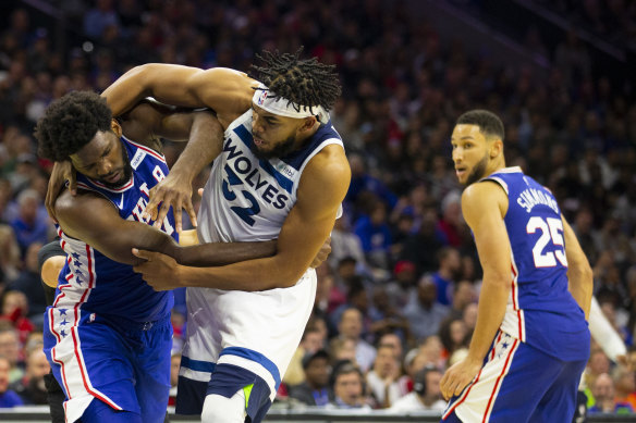 Embiid and Towns clash, with Simmons in the background.