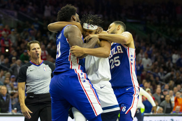 Joel Embiid and Karl-Anthony Towns wrestle as Ben Simmons appears to attempt to break up the scuffle.