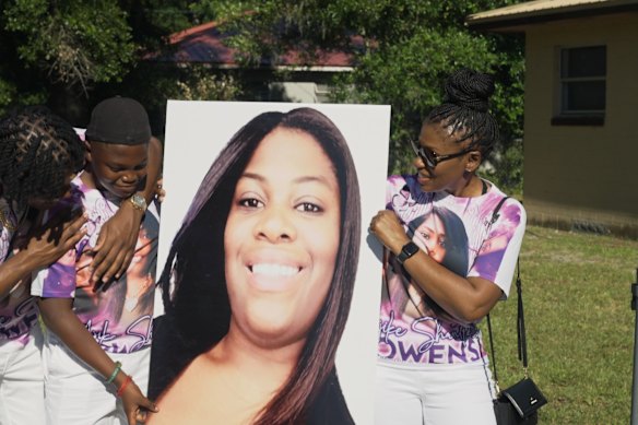 Family members hold aloft a photo of Ajike Owens at her memorial service.