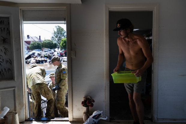 Members of the ADF join up with community volunteers to clear the house of an elderly couple.