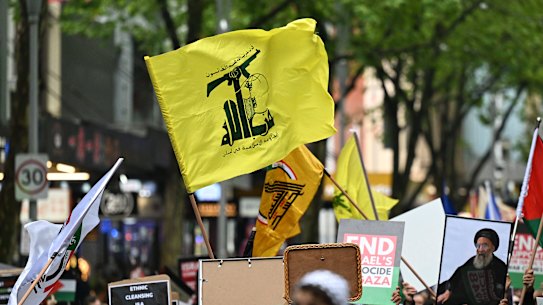 Protesters raise the flag of Hezbollah, a proscribed terrorist group, outside the State Library of Victoria on Sunday.
