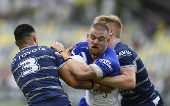 Bulldogs fullback Matt Dufty is stopped by Valentine Holmes and Tom Dearden, two of the Cowboys best in 2022.