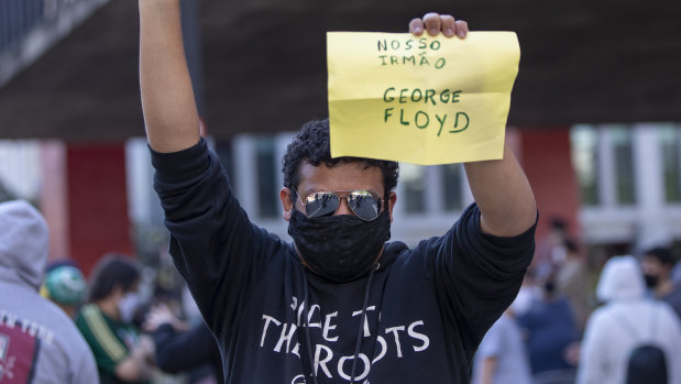 An anti-government demonstrator holds a sign that reads in Portuguese "Our brother George Floyd," during a protest in Sao Paulo on Sunday.