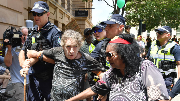 A protester (centre) is led away by police during the rally in Brisbane.