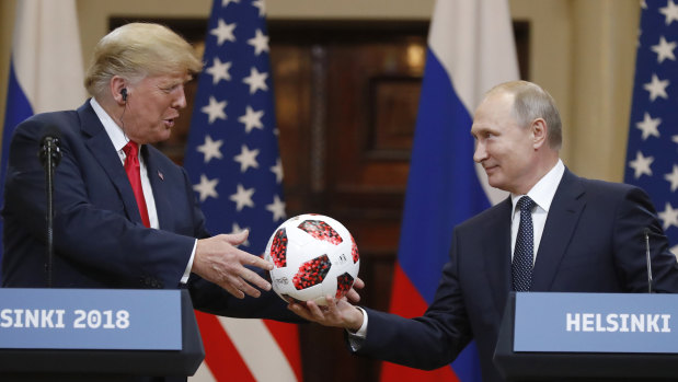 President Vladimir Putin gives a soccer ball to US President Donald Trump during their press conference on Monday.