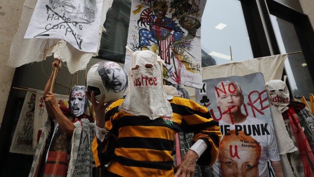 British Fashion designer Vivienne Westwood, centre, with her head covered, poses for photos during a protest to support Julian Assange outside the Central Criminal Court Old Bailey in London.