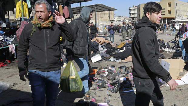 People and security forces gather at the site of a deadly bomb attack in Baghdad, Iraq.