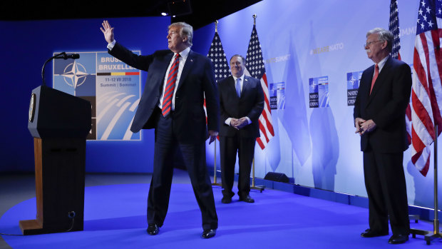 Trump, with Secretary of State Mike Pompeo and National security adviser John Bolton, waves as he walks off stage.