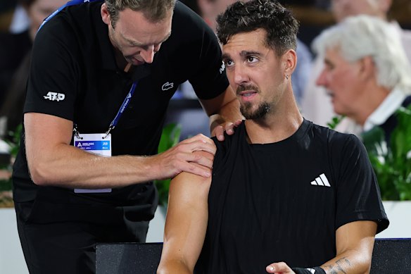 Thanasi Kokkinakis in the hands of a physio during his Adelaide International match against Sebastian Korda.