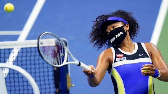 Naomi Osaka, wearing a mask in tribute to George Floyd, fires a ball in celebration after beating Shelby Rogers.