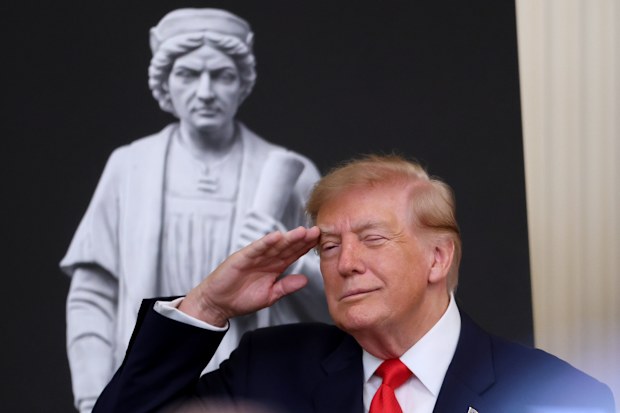 President Donald Trump salutes during the singing of the national anthem at a Columbus Day celebration.