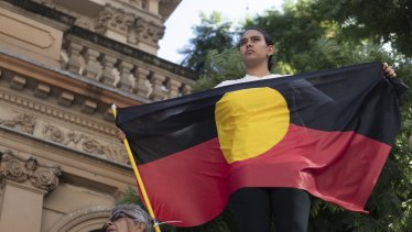 A protester holds an Aboriginal flag at a rally in Sydney to mark 30 years since the royal commission.