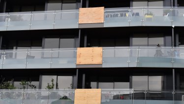 Balconies in this Melbourne apartment building have been patched up with wood following multiple glass explosions. 